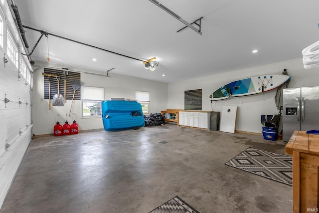 garage with stainless steel fridge with ice dispenser, recessed lighting, and a garage door opener