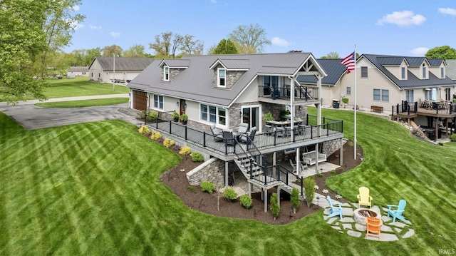 rear view of house featuring stone siding, a fire pit, a wooden deck, stairs, and a balcony