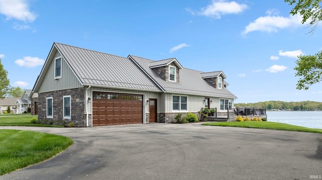 view of front of property featuring stone siding, a water view, driveway, metal roof, and a standing seam roof