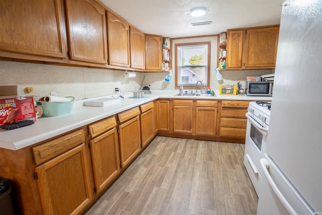kitchen featuring white appliances, open shelves, a sink, light wood-style floors, and light countertops