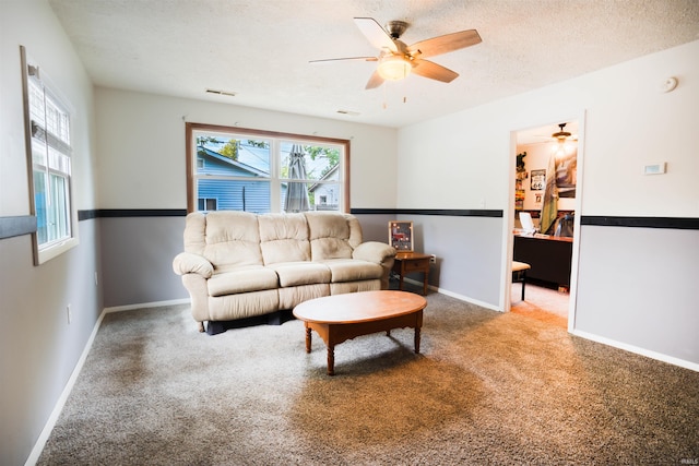 carpeted living room with ceiling fan, baseboards, and a textured ceiling
