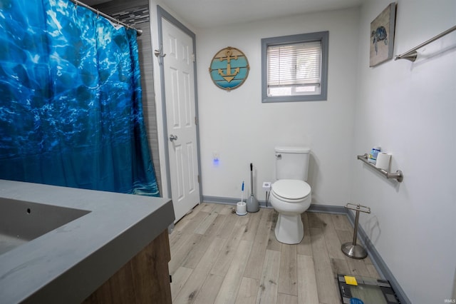 bathroom with wood finished floors, toilet, baseboards, a shower with curtain, and vanity