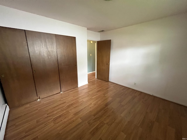 3212 S Saint Joseph St, South Bend, IN 46614 - unfurnished bedroom featuring a baseboard radiator, wood finished floors, a closet, and baseboards