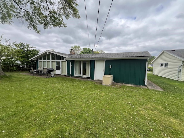 3212 S Saint Joseph St, South Bend, IN 46614 - rear view of house with board and batten siding, a lawn, a chimney, and a patio area