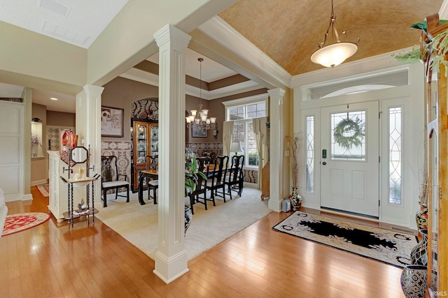 entrance foyer with decorative columns, light wood-type flooring, a chandelier, ornamental molding, and baseboards
