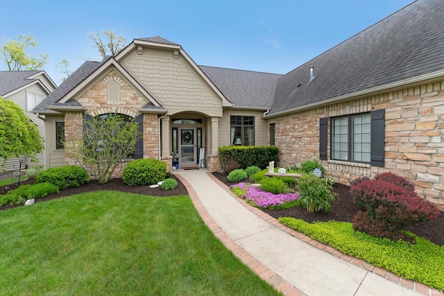 view of front facade with stone siding, a front lawn, and a shingled roof
