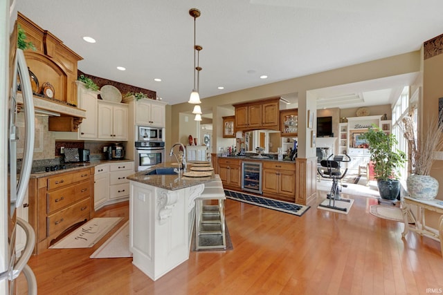 kitchen featuring wine cooler, stainless steel appliances, a sink, light wood-type flooring, and recessed lighting