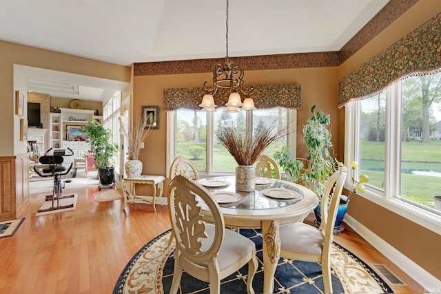 dining space featuring a chandelier, plenty of natural light, wood finished floors, and baseboards