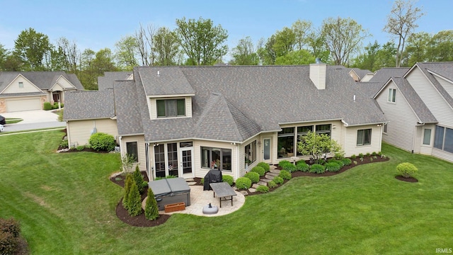rear view of property with a patio area, a lawn, roof with shingles, and a chimney