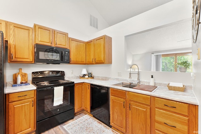 6114 Picacho Dr, Fort Wayne, IN 46825 - kitchen with black appliances, light wood-style flooring, lofted ceiling, a sink, and light countertops