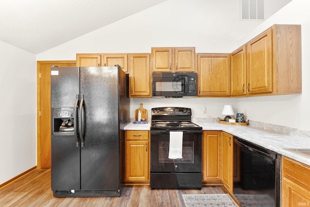 6114 Picacho Dr, Fort Wayne, IN 46825 - kitchen with black appliances, lofted ceiling, light wood finished floors, and light countertops