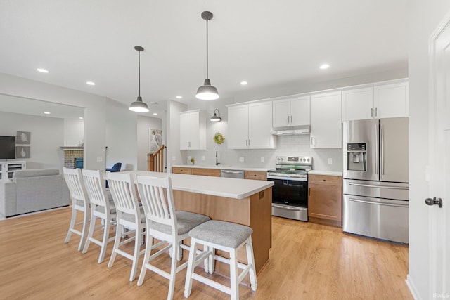 1004 Hathaway Rd, Fort Wayne, IN 46845 - kitchen featuring stainless steel appliances, under cabinet range hood, light wood-style floors, a kitchen bar, and recessed lighting
