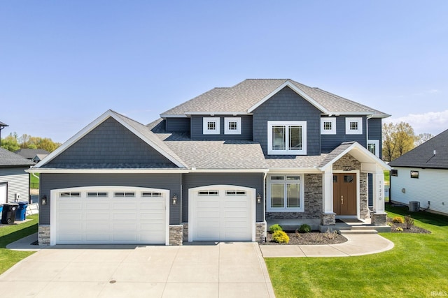 craftsman-style house featuring stone siding, driveway, a garage, a front lawn, and roof with shingles