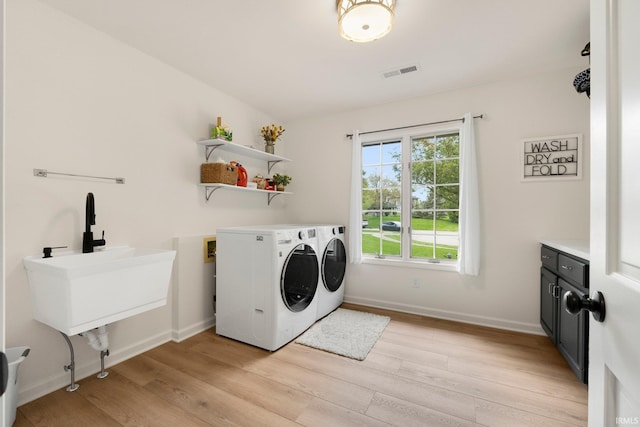 laundry area with washing machine and dryer, light wood-style floors, baseboards, and a sink