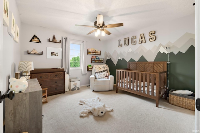 bedroom with a crib, carpet flooring, and ceiling fan