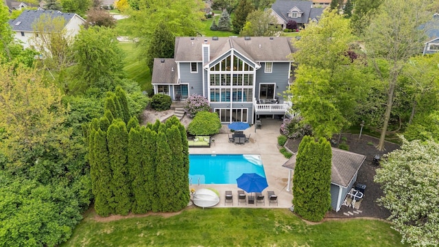 rear view of house featuring a patio, a wooden deck, an outdoor pool, a sunroom, and a lawn