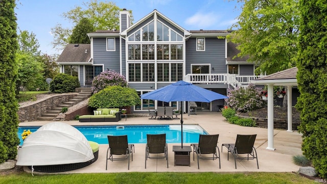 back of property featuring stairway, a chimney, a patio, outdoor lounge area, and an outdoor pool