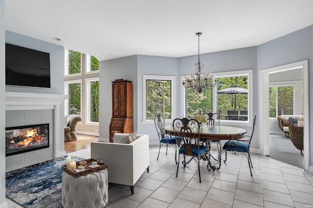dining room with plenty of natural light, a chandelier, a tile fireplace, and baseboards