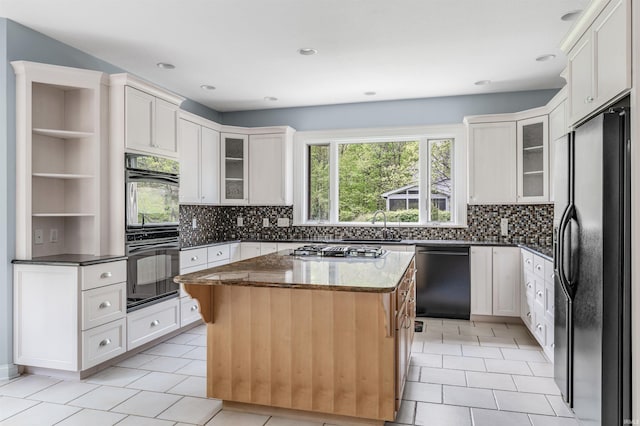 kitchen featuring black appliances, tasteful backsplash, dark stone countertops, glass insert cabinets, and recessed lighting