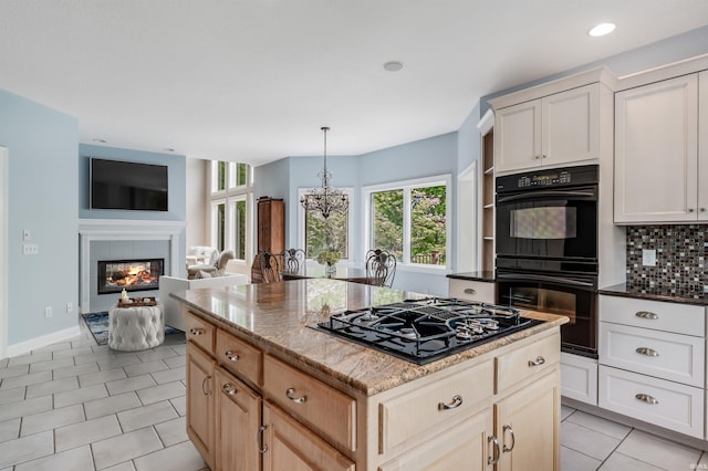 kitchen featuring black appliances, plenty of natural light, a chandelier, dark stone counters, and recessed lighting