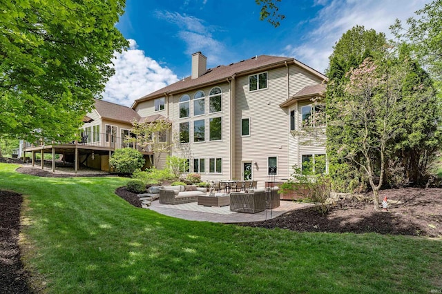 rear view of house featuring outdoor lounge area, a chimney, a lawn, a wooden deck, and a patio