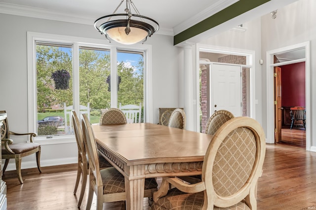 dining room with a chandelier, wood finished floors, crown molding, and baseboards