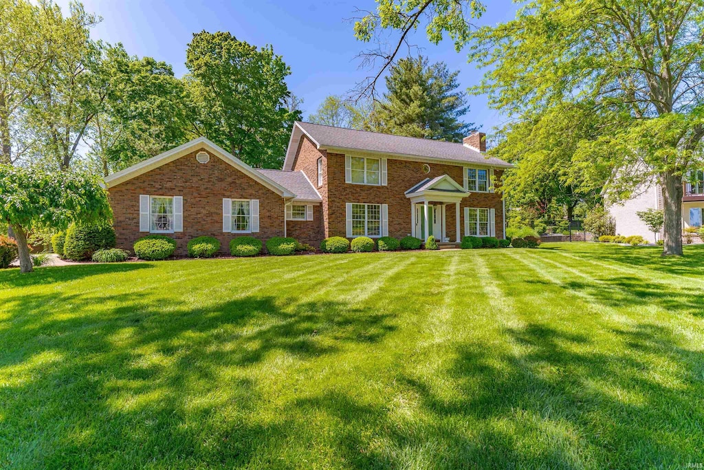 6811 Old Stonehouse Dr, Newburgh, IN 47630 - colonial house featuring a chimney, a front lawn, and brick siding