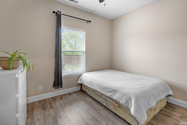 bedroom featuring baseboards, wood finished floors, and a ceiling fan