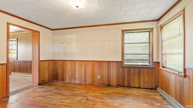 800 E 900 N, Decatur, IN 46733 - empty room featuring light wood-style floors, a baseboard radiator, crown molding, wainscoting, and wood walls
