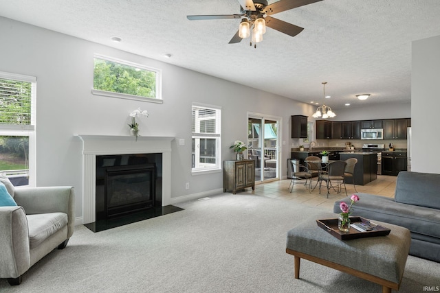living area featuring a chandelier, a fireplace with flush hearth, plenty of natural light, and a textured ceiling