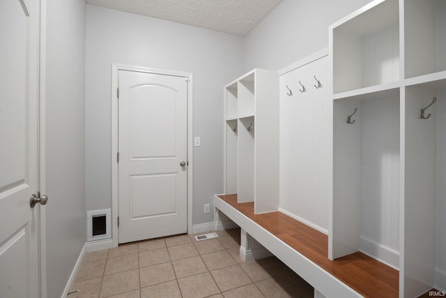 mudroom featuring light tile patterned floors, a textured ceiling, and baseboards