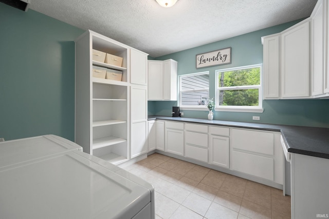 clothes washing area with cabinet space, a textured ceiling, light tile patterned flooring, and washer and clothes dryer