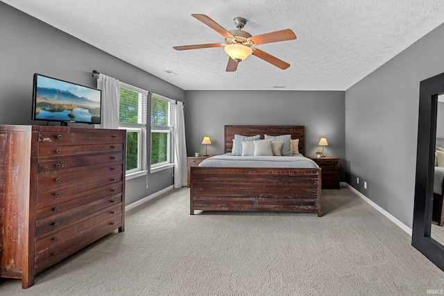 bedroom with light colored carpet, a textured ceiling, baseboards, and ceiling fan