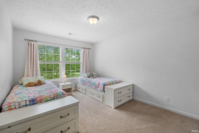 bedroom featuring light carpet, a textured ceiling, and baseboards