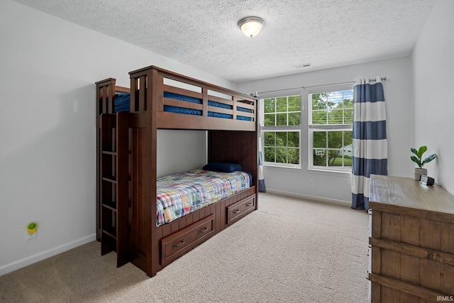bedroom featuring light colored carpet, baseboards, and a textured ceiling