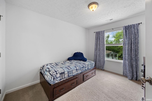 carpeted bedroom featuring a textured ceiling and baseboards