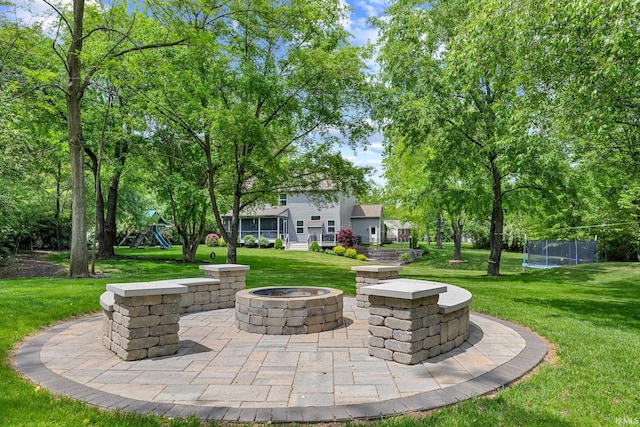 view of patio / terrace featuring an outdoor fire pit, a playground, and a trampoline
