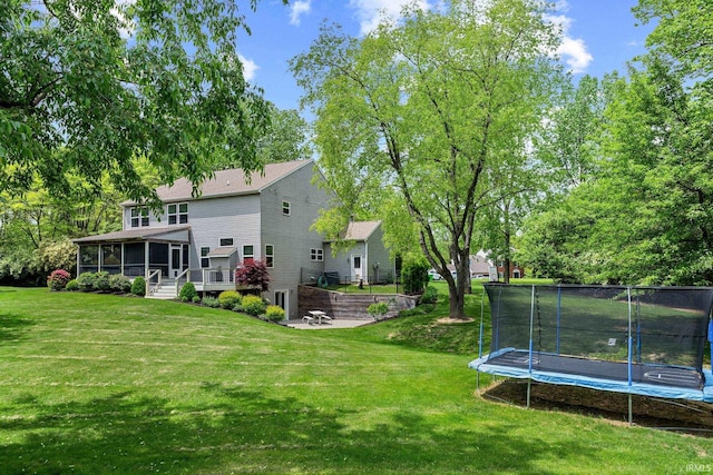 view of green lawn featuring a sunroom, a trampoline, and a patio