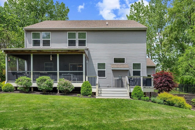 rear view of house with a sunroom, a lawn, roof with shingles, and a wooden deck