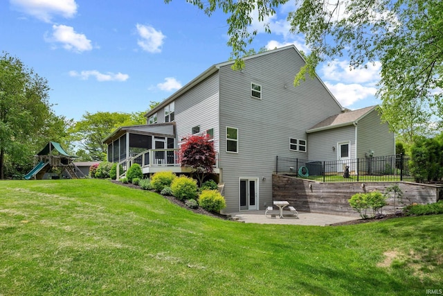 rear view of property featuring a sunroom, a patio, and a playground