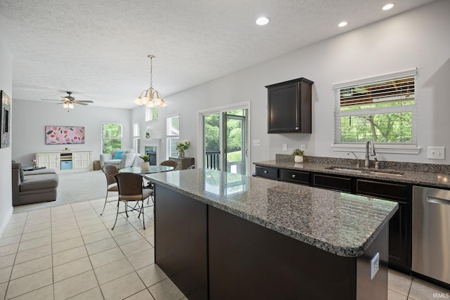 kitchen with dishwasher, a sink, a textured ceiling, a kitchen island, and light colored carpet