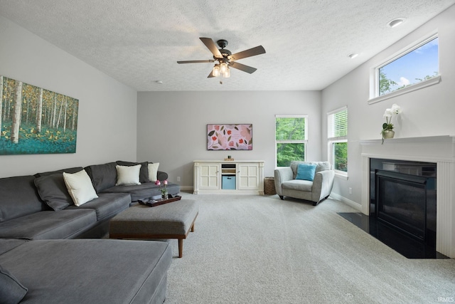 living room featuring carpet floors, a textured ceiling, baseboards, ceiling fan, and a fireplace with flush hearth