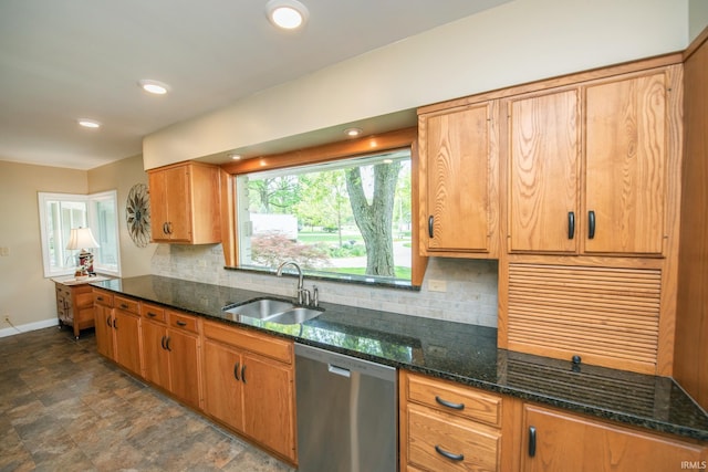 kitchen featuring stainless steel dishwasher, a sink, backsplash, baseboards, and dark stone counters