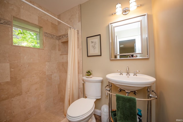 full bathroom featuring toilet, tiled shower, and a sink