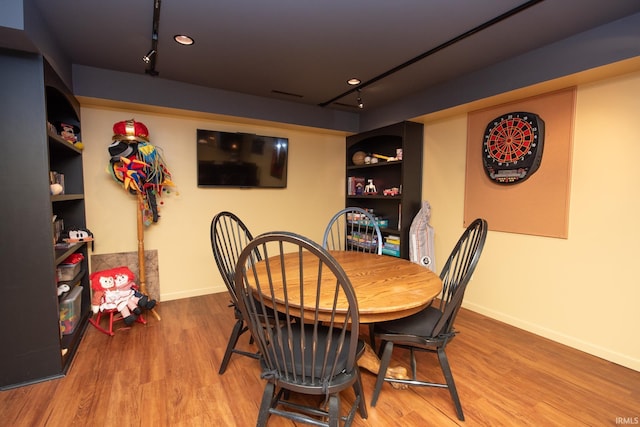 dining room featuring track lighting, wood finished floors, and baseboards
