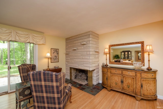 sitting room with light wood-type flooring, a fireplace, and baseboards