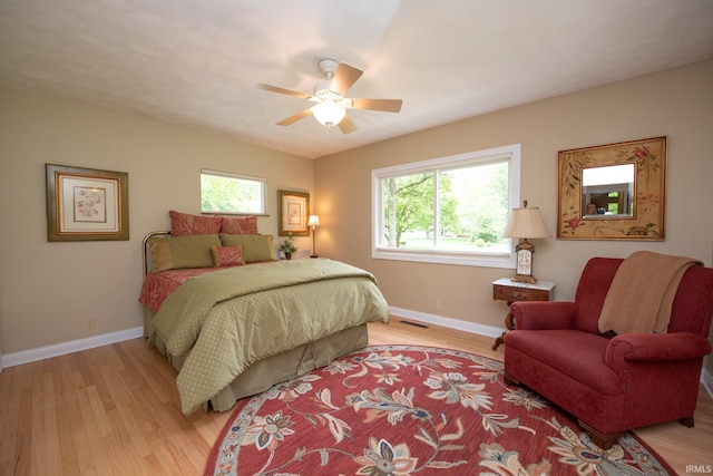 bedroom featuring multiple windows, light wood finished floors, and baseboards