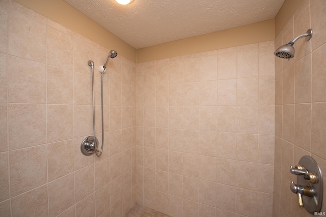 bathroom with a tile shower and a textured ceiling