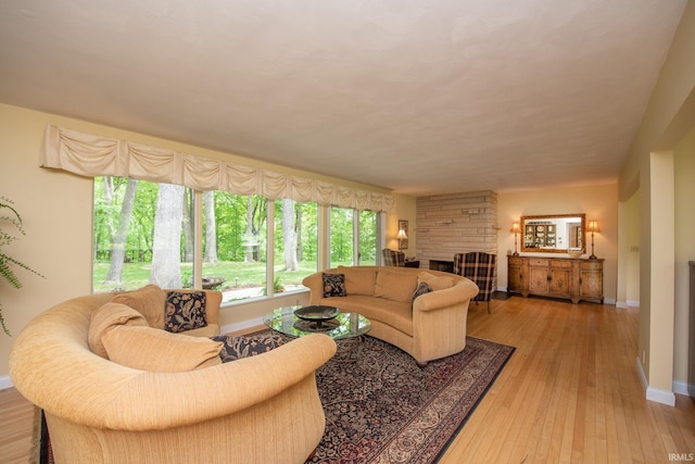 living area with baseboards, light wood-style floors, and a fireplace