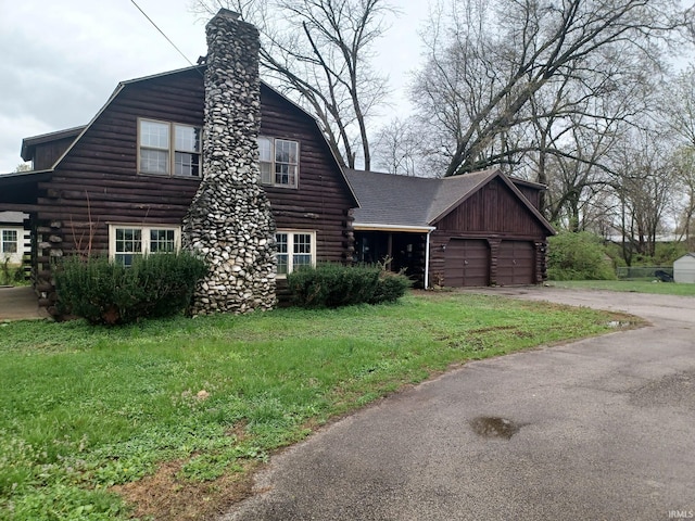 403 E Poplar St, Fort Branch, IN 47648 - view of front of property featuring log siding, a garage, driveway, a front yard, and a chimney